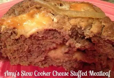 A slice of meatloaf on a red plate, stuffed with cheese oozing out.
