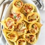 Lasagna Rolls in a white oval casserole dish with a grey, striped napkin in the background.