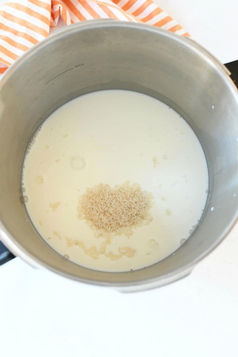 Rice in milk inside a large stockpot with an orange striped napkin.