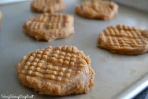 Raw, cross-hatch peanut butter cookies on a baking sheet.