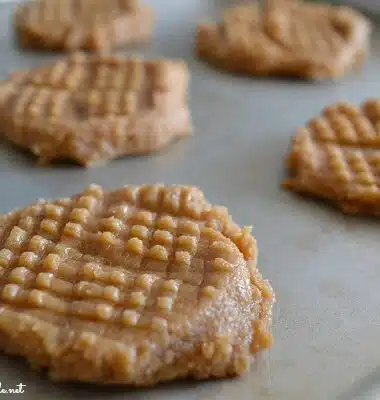 Raw, cross-hatch peanut butter cookies on a baking sheet.