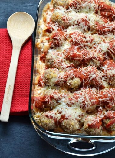 Turkey Meatball Casserole in a clear, glass Pyrex with a red napkin and wooden spoon.