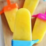 Holding orange ice pops in colorful molds.