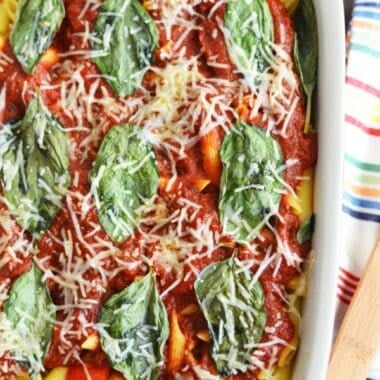Mushroom pasta with parmesan cheese, and fresh basil in a white, rectangle baker.