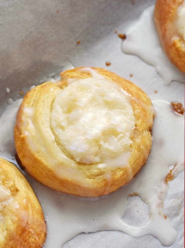 Cream Cheese Danish in a pool of icing on a baking dish. 