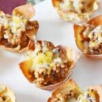 Crispy, golden-browned sausage and cheese baked wontons on a white platter.
