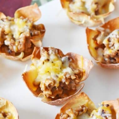 Crispy, golden-browned sausage and cheese baked wontons on a white platter.