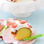 Slice of Strawberry Lemon Cake on a pink plate with a green fork.