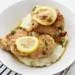 Lemon Chicken with Mashed Potatoes with lemon slices over mashed potatoes.