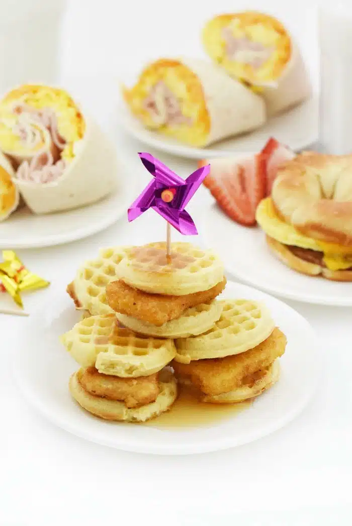 Mini Chicken and Waffles sliders on white plate with purple pinwheel in the center