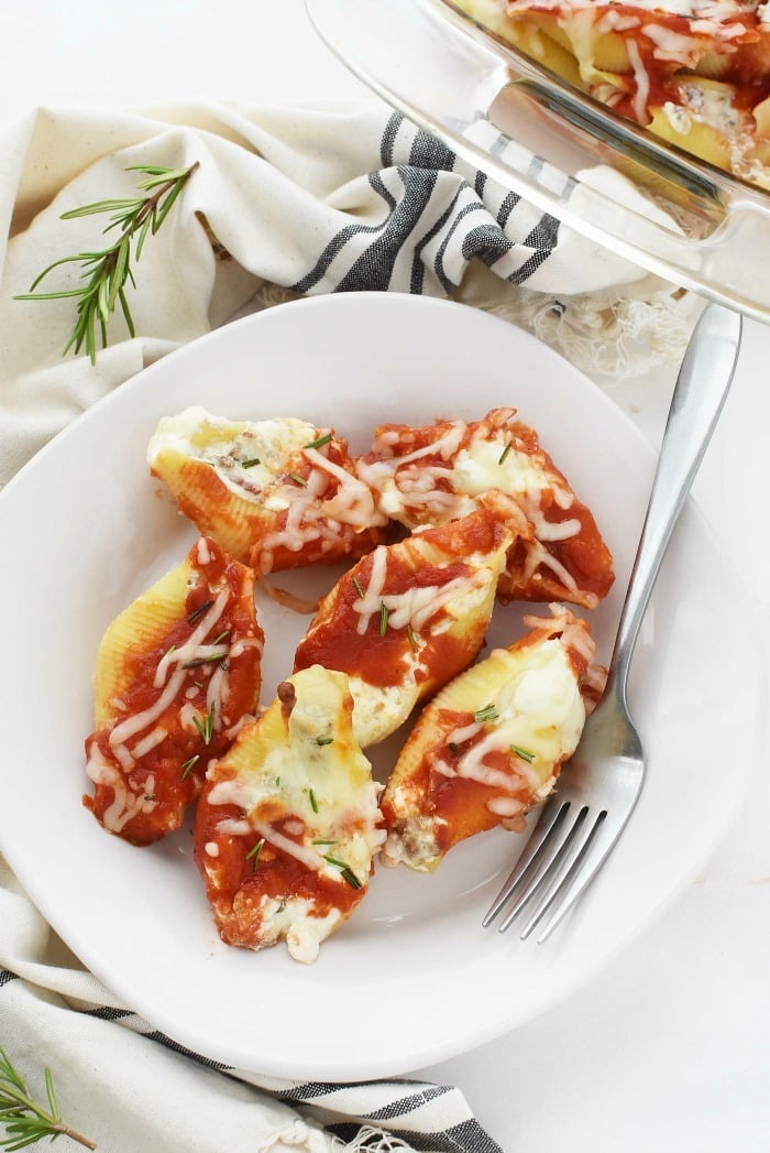 Sausage and Bacon Stuffed Shells on white plate with striped grey napkin. 