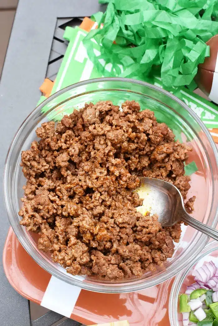 Slow cooker Taco beef in a clear, glass bowl with a spoon.