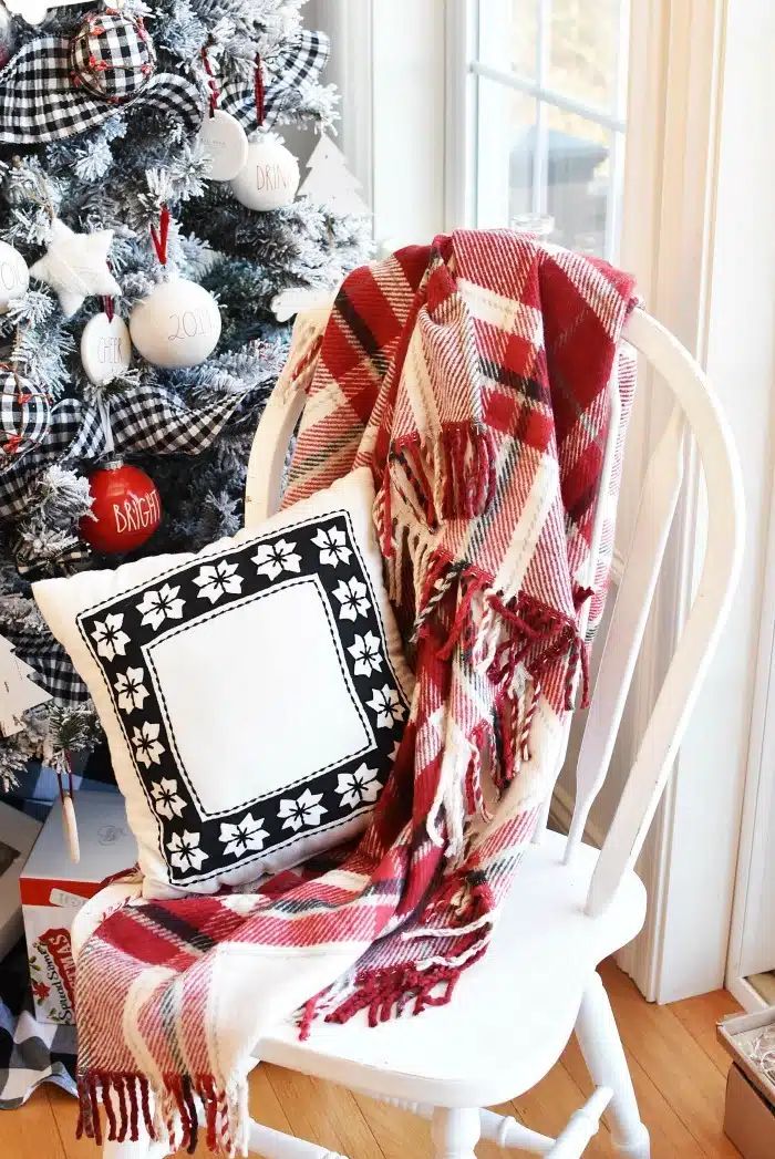 Farmhouse Styled Chair with black and white pillow and red plaid throw.
