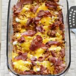 Chicken bacon ranch casserole bake topped with melted cheese and crispy bacon pieces inside glass pyrex dish.