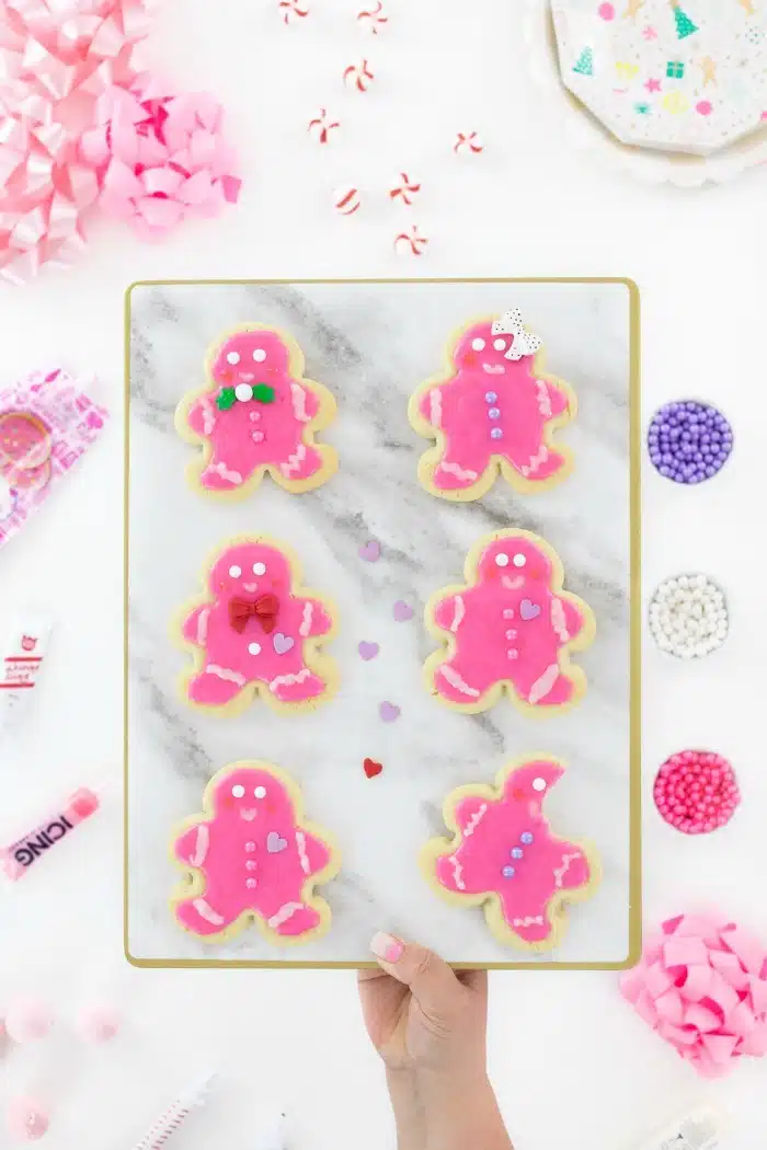 Pink Gingerbread men on a granite board in someone's hand. 