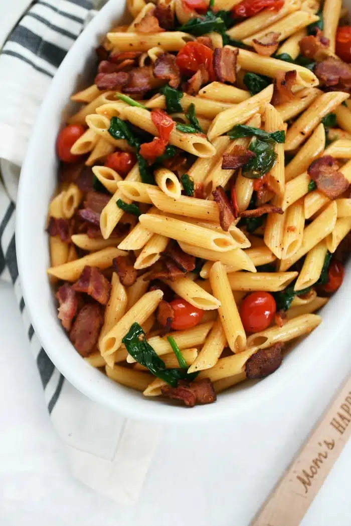 BLT Pasta Recipe in an oval dish with a striped napkin. 