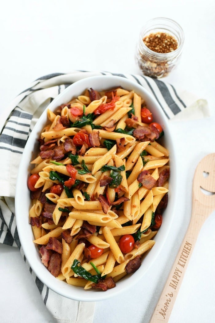 BLT Penne Pasta in a white oval dish with a wooden spoon. 