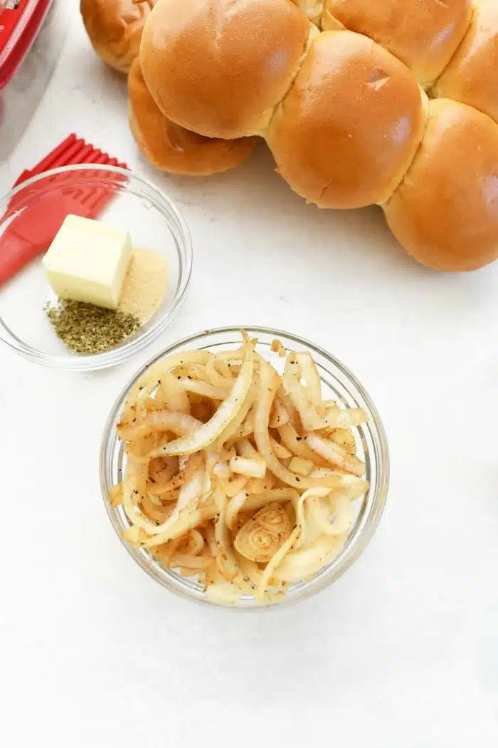 Caramelized Onions with butter, spices, and buns on white table.