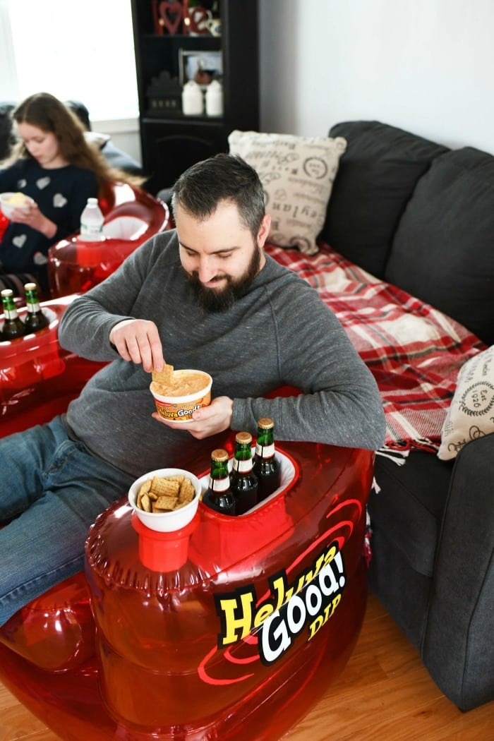 Man sitting on Heluva Good best seat in the house chair with chips and dip. 