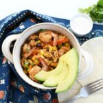 One-Pot Mexican Shrimp in a white handled bowl with fresh sliced avocado.
