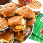 Roast Beef French Onion Sliders with melty cheese on a white platter near Heluva Good dip cups.