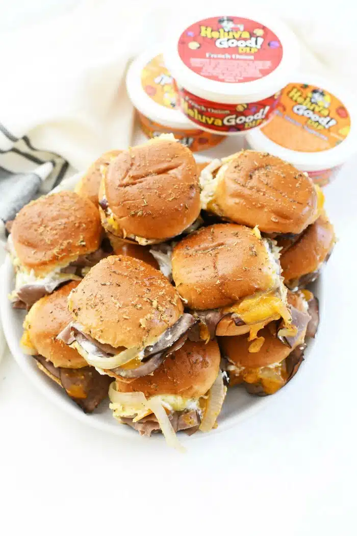 Cheddar and roast beef sliders on platter with dip.