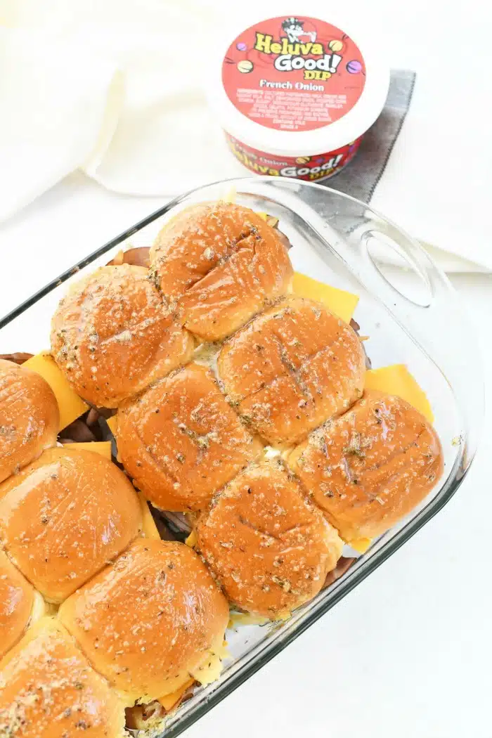 Roast Beef sliders prebaked in glass dish on white table.