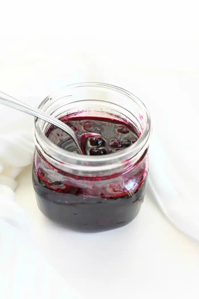 Blueberry topping in glass jar with white napkin. 