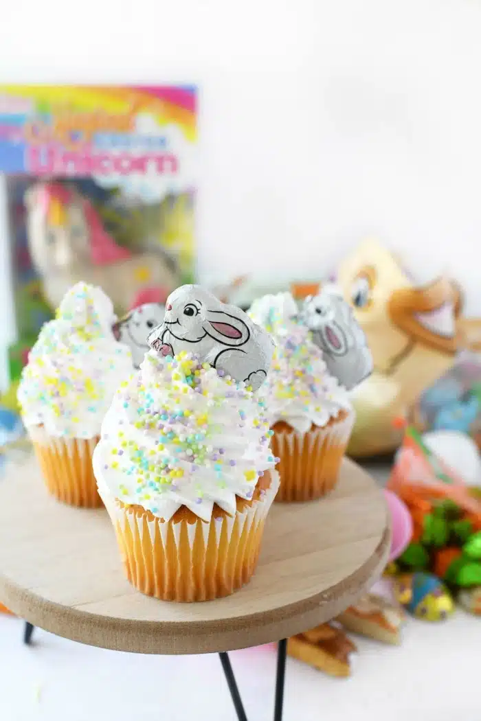 Easter Bunny Cupcakes with sprinkles on wooden stand. 