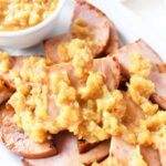 Ham steak with pineapple topping on a white platter.