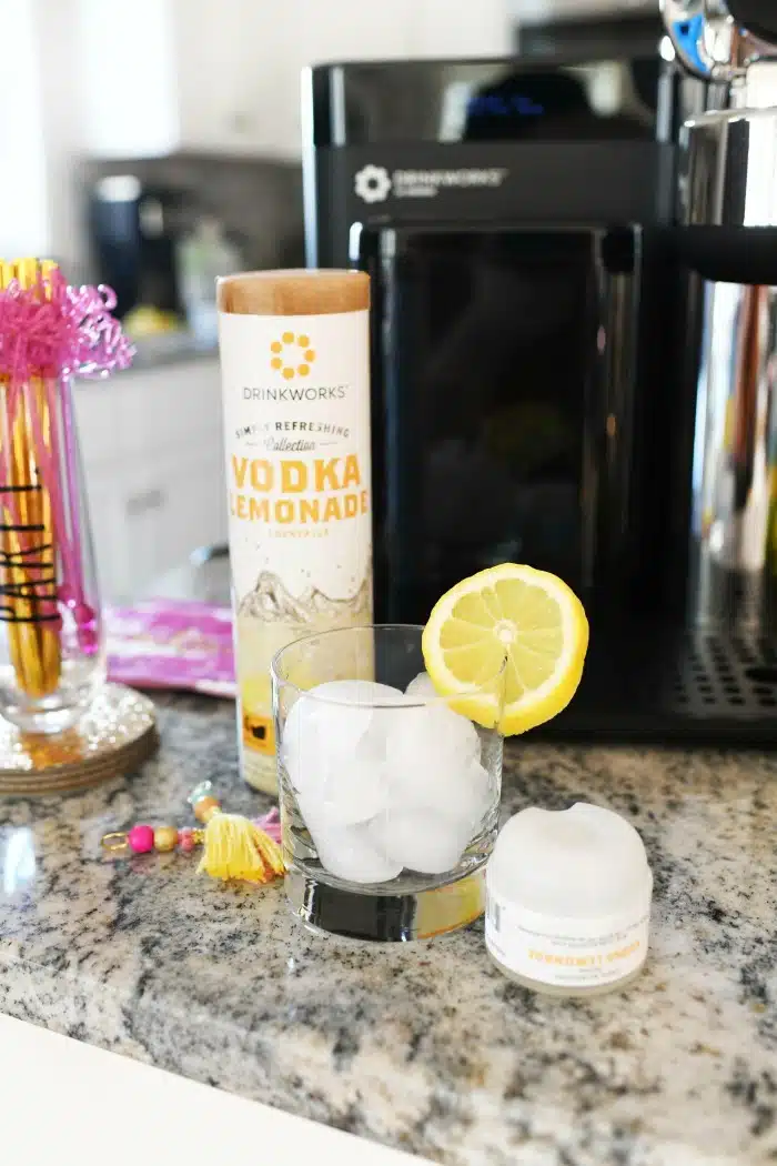 Vodka Lemonade pod near a glass of ice with lemon slice. 
