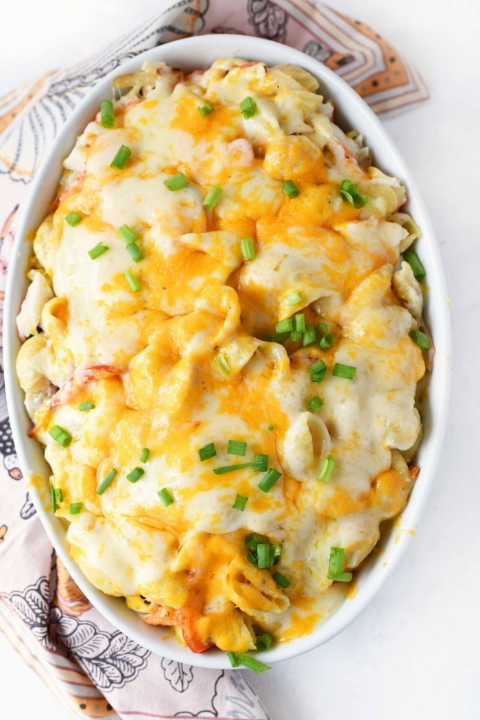 Cheese Crab casserole with baked cheese on a white table with a patterned napkin around. 
