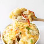 Crab Meat Casserole on a wooden spoon with a cheese pull.
