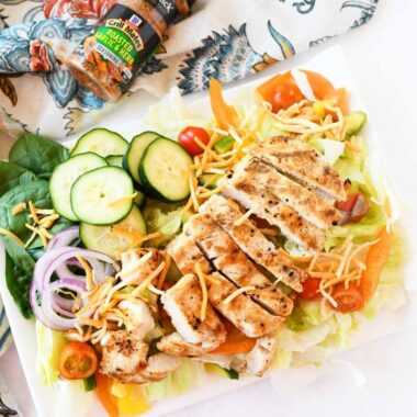 Grilled Chicken on salad on white plate with patterned napkin