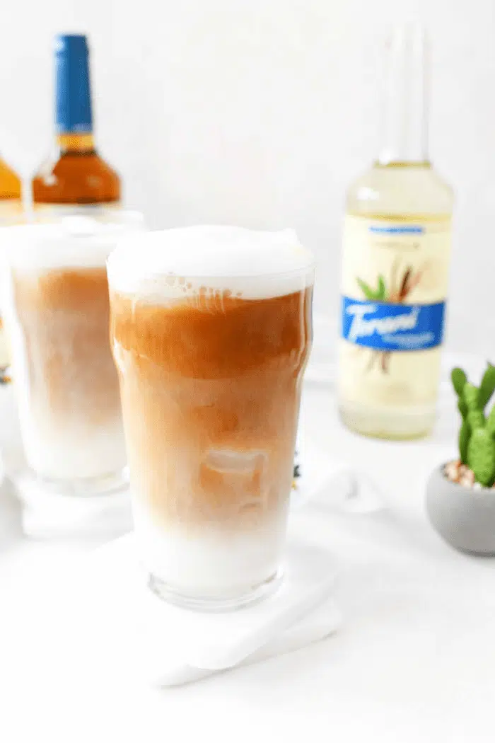 Iced tea latte in glass on white background