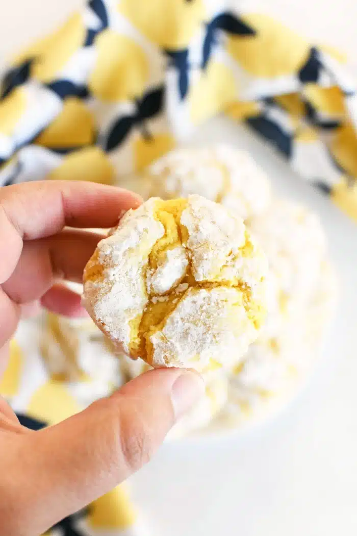 Lemon Cake mix cookie in a women's hand. A lemon napkin is in the background. 