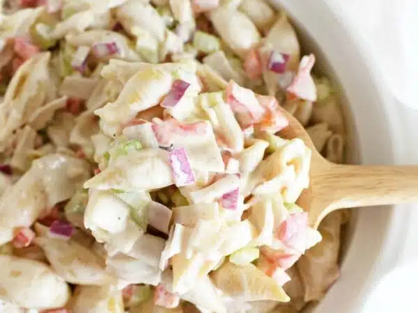 Seafood salad in white dish with white napkin and wooden spoon