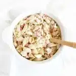 Crabmeat pasta salad in white dish with a wooden spoon.