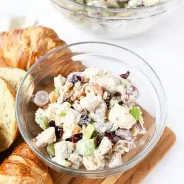 Chunky chicken salad in a glass bowl with croissants.