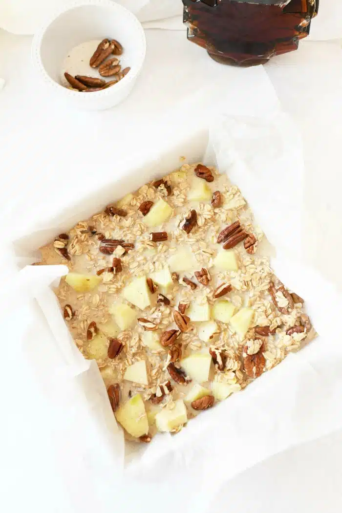 Baked oatmeal with apples prebaked in a white lined dish.