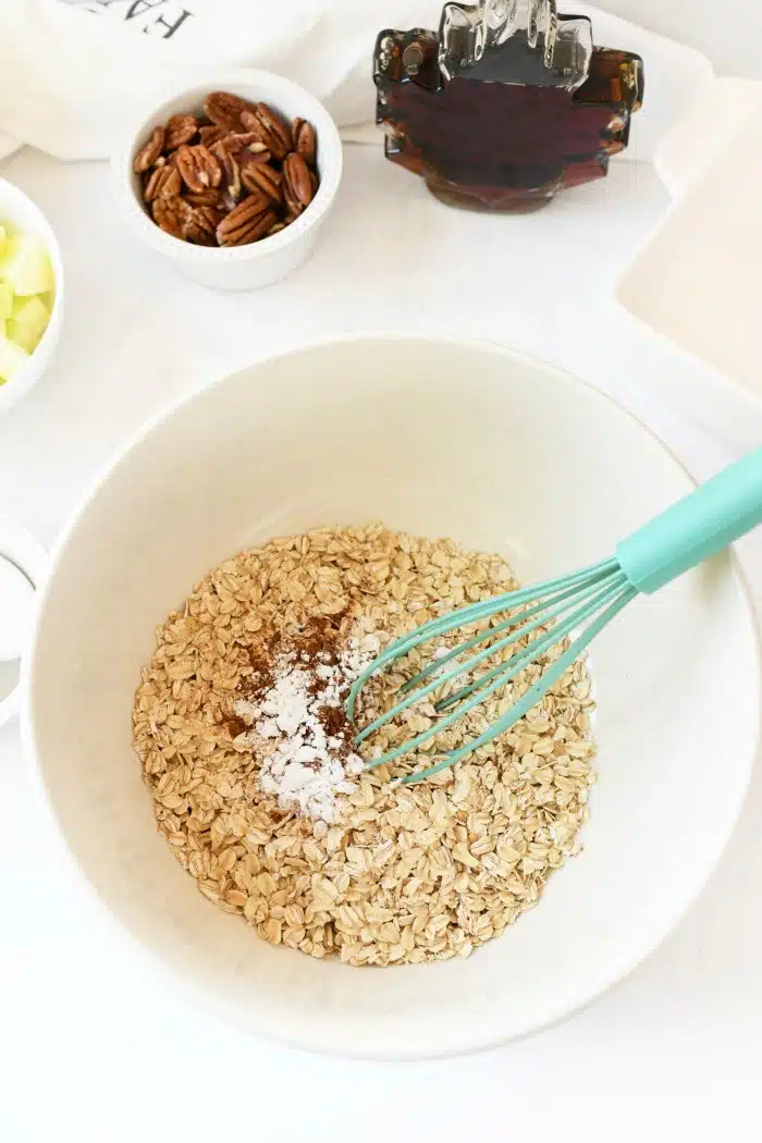  oatmeal ingredients in a large bowl with a blue whisk.