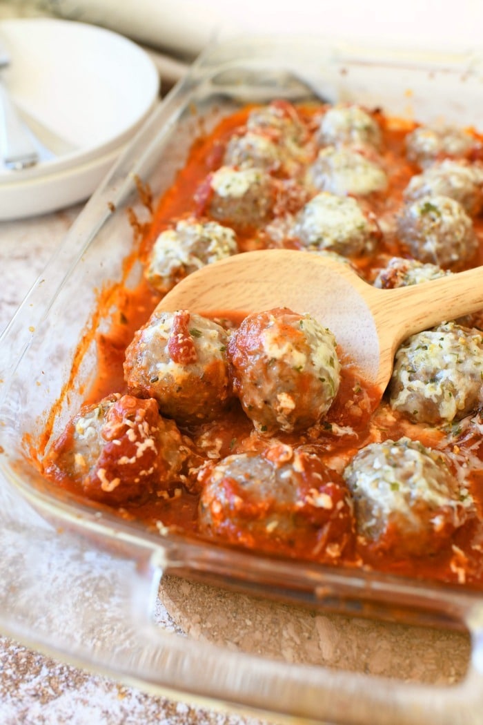 Cheesy Meatball Casserole with a wooden spoon.