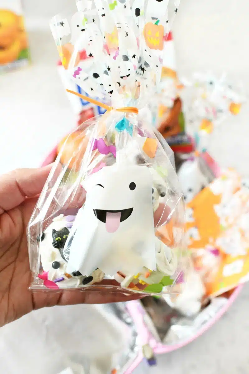 A hand holding a ghost treat bag.