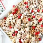 Buddy The Elf Chex Mix on a white parchment lined baking sheet with a white Christmas napkin.