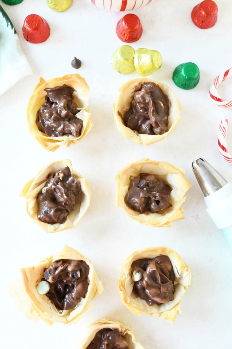 Mint chocolate crème pie shells filled with chocolate lined up on a white table. 