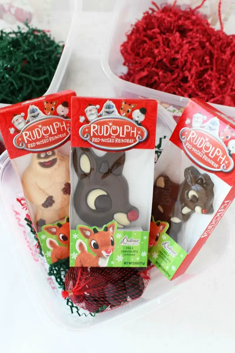 Rudolph Chocolate Candy on a white table near red and green filled boxes. 