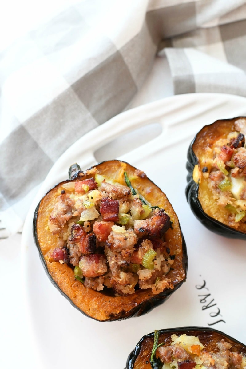 Sausage & Bacon Stuffed Acorn Squash on a white tray with a gray napkin.