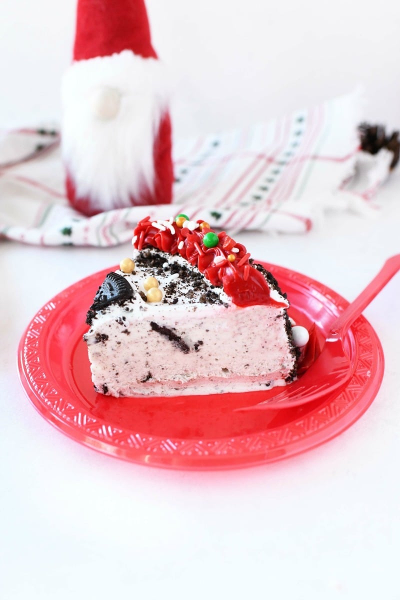 Slice of OREO ice cream cake on a red plate with a gnome in the background.