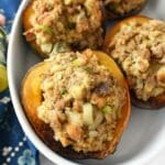 Sausage Stuffed Baked Acorn Squash in a white oval baker with a blue, floral napkin.
