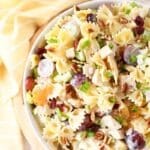 A colorful, tropical chicken salad with a yellow striped napkin nearby.